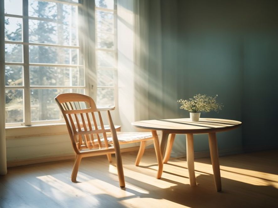 Sunlight streaming through a window onto a chair and wooden table